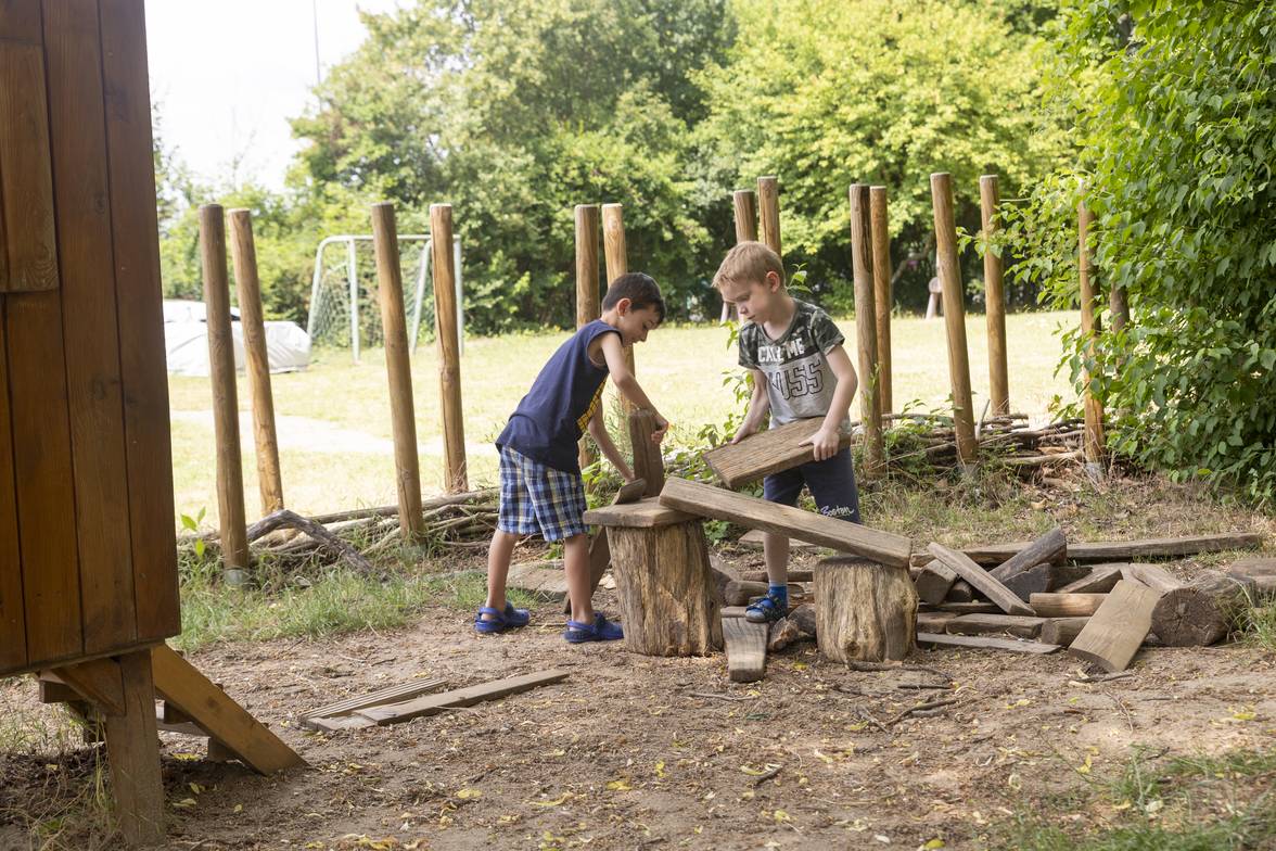 Zwei Kinder bauen draußen etwas aus Holzelementen